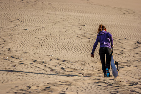 Picture of a young woman sandboarding at sunset, Huacachina, Ica, Peruの写真素材