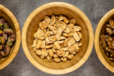 Peanuts and pistachios in wooden bowl on gray background.の写真素材