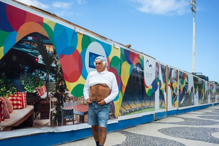 Rio De Janeiro, Brazil  - September 6, 2013: An elderly man walking on the seafront of Copacabana beachのeditorial素材