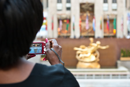 New York, U.S.A. - October 7, 20010: Manhattan, a woman taking a photograph in Rockefeller Centerのeditorial素材
