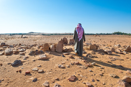 Al Jouf,  Saudi Arabia - November 26, 2008: Local people in the  Rajajil archaeological site with the prehistoric standing stone.のeditorial素材
