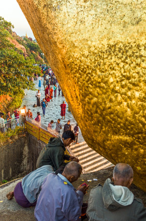 Kyaikhto,  Myanmar - January 10, 2012: Religious  in prayer under the delicately balanced golden Stupa on the sacred Buddhist mountainのeditorial素材