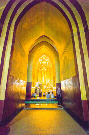 Bagan,  Myanmar - January 12, 2012: People in the Ananada temple with the golden Buddha statueのeditorial素材