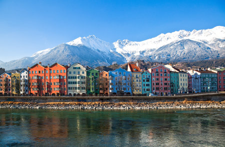 Innsbruck, Austria - February 8, 2010:  The Mariahilf strasse colored houses on the Inn river with the snowy mountains in the backgroundのeditorial素材