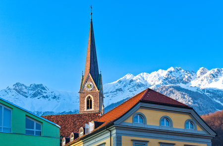 Austria, Tyrol, Innsbruck, view of  the snowy mountains fom the Inn river bank with old houses and bell tower in the foregroundのeditorial素材