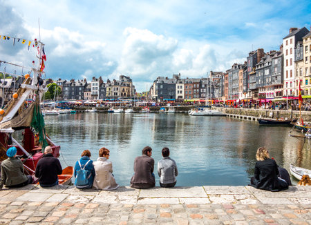Honfleur, France - May 19, 2012: Normandy, tourists, traditional houses and boats in the old harbor basin.のeditorial素材