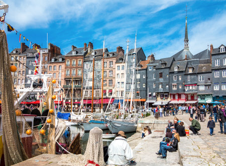 Honfleur, France - May 19, 2012: Normandy, tourists, traditional houses and boats in the old harbor basin.のeditorial素材