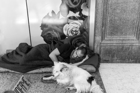 Milan, Italy - July 5, 2014: An  homeless man with his dog, sleeping in front of a shopwindow  in Corso Vittorio Emanueleのeditorial素材