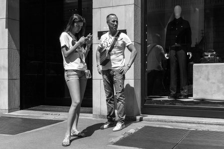 Milan, Italy - July 5, 2014: A  young woman while phoning in front of a fashion store in Montenapoleone streetのeditorial素材