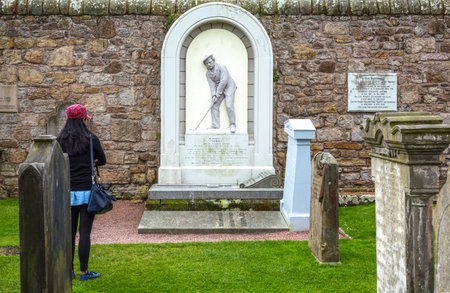 St Andrews, Scotland - July 26, 2012:  Fife area, a young tourist looking at a golfer tomb in the Cathedral's cemeteryのeditorial素材