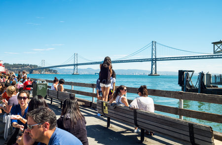 San Francisco, USA - September 26, 2015: Tourists on the pier of the Ferry Building with the Bay Bridge on backgroundのeditorial素材