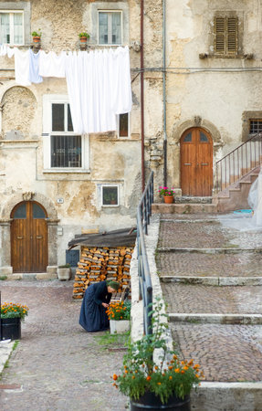 Scanno, Italy - August 18, 2006: An old local woman in traditional dress between the typical ancient architectures of the country centerのeditorial素材