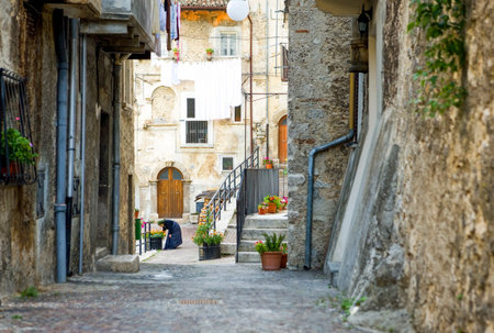 Scanno, Italy - August 18, 2006: An old local woman in traditional dress between the typical ancient architectures of the country centerのeditorial素材