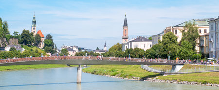 Salzburg, Austria - August 3, 2016:  People crossing a bridge on the Salzach river with the old town in the backgroundのeditorial素材