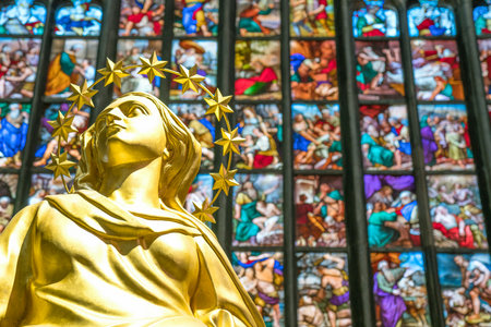 Milan, Italy - October 27, 2016: The interior of the Duomo Cathedral, the colorful stained glass of the apse with the golden statue of the Madonna in the foregroundのeditorial素材