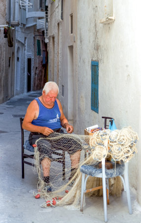 Monopoli, Italy - Juky 21, 2006: A senior fishermen working on the net in the old townのeditorial素材