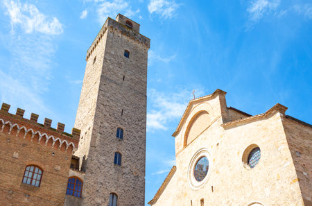 San Giminiano, Italy , upward view of the Cathedral facade and a medieval tower in Duomo squareの写真素材