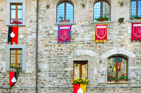 Italy,Umbria,Gubbio, Dei Consoli street, the  facade of a medieval house with gonfalons of the districts of the townのeditorial素材