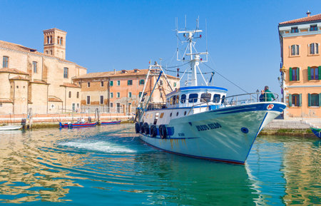 Chioggia, Italy - March 2, 2012:  A fishermen boat returns to the canal harborのeditorial素材