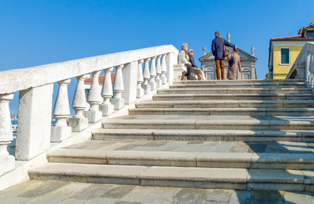 Chioggia, Italy - March 2, 2012: Local seniors sunbathing on  the San Domenico bridgeのeditorial素材