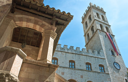 Assisi, Italy - May 21,2009: The upward view of the Del Popolo towervith the loggia of the Dei Priori palace in the foregroundのeditorial素材