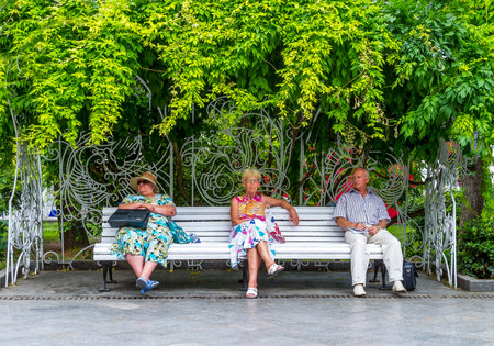 Jalta, Ukraine - August 16, 2012: Local people people sitting on a bench in the waterfront pedestrian walkway along the Black Seaのeditorial素材