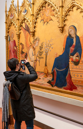 Florence, Italy - February 15, 2019: The Uffizi Gallery, sacred paintings from the fourteenth century, with a visitorのeditorial素材