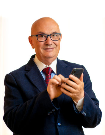 Senior Business Man using a smartphone in a white backgroundの写真素材