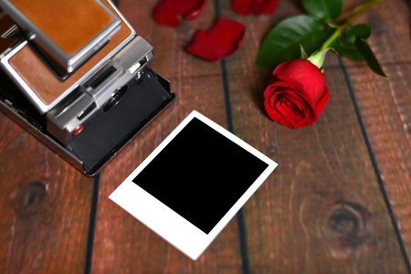 Vintage red rose camera with petals and instant photo on wooden slats love giftの写真素材
