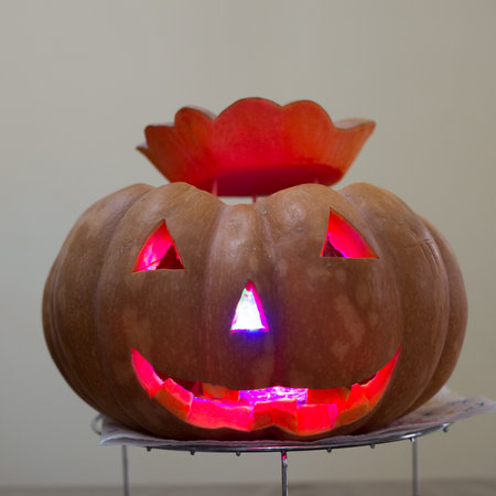 Orange pumpkin with orange eyes, nose and mouth with lighted eyes, nose and mouthの写真素材
