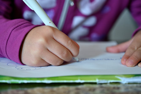 little girl with a pen on a white sheetの写真素材