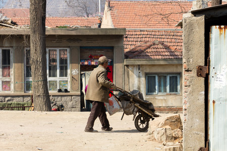 March 2014 - Qingdao, China - A man dragging a cart in the poor neighborhood of Shandongtouのeditorial素材