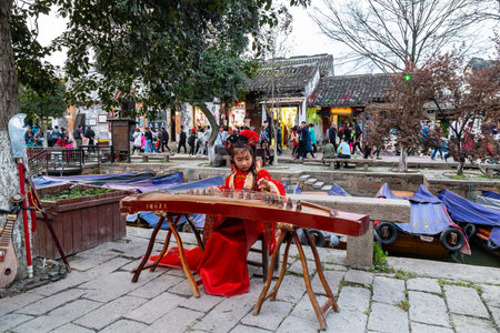 Mar 2017 - Tongli, Jiangsu, China? Girl in a traditional Chinese red dress playing Guzheng along the canals of Tongli, one of the famous watering villagesのeditorial素材