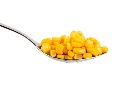 Canned corn in a spoon is isolated on a white backgroundの写真素材