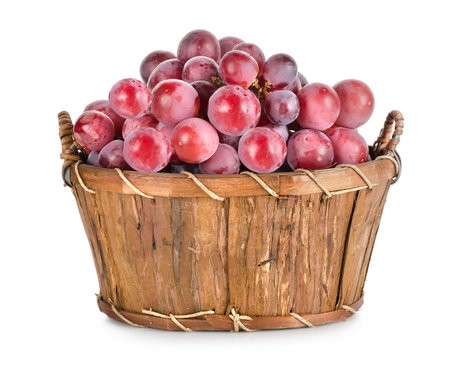 Dark blue grapes in a wooden basket isolatedの写真素材