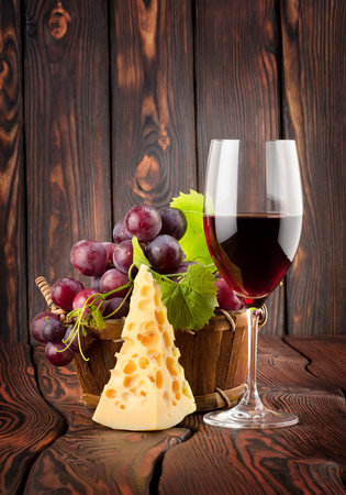 Wine glass and cheese in a basket on a wooden backgroundの写真素材