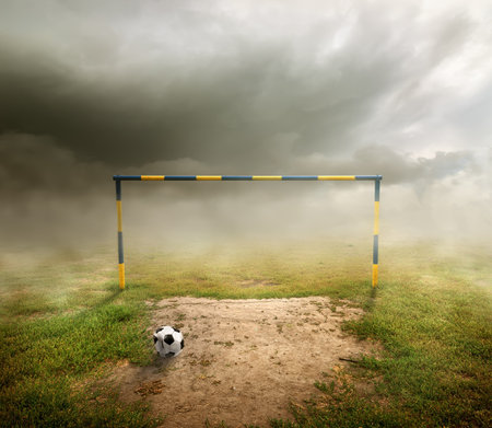 Football field, football goal, deflated ball and cloudy skyの写真素材