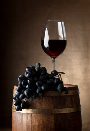 Wine goblet with wooden barrel and grapeの写真素材