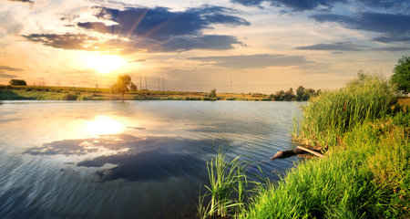 Reflection of clouds in a calm river at sunsetの写真素材