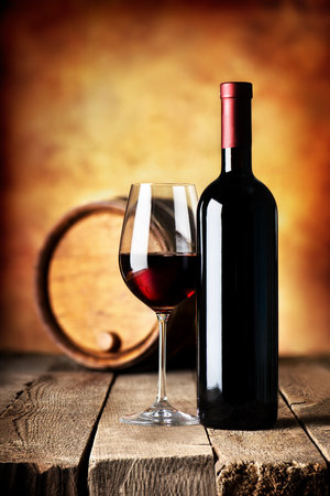 Red wine in bottle and cask on a wooden tableの写真素材