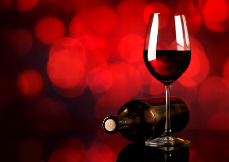 Red wine in wineglass and bottle on red backgroundの写真素材
