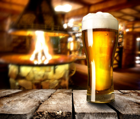 Beer on wooden table in bar with furnaceの写真素材