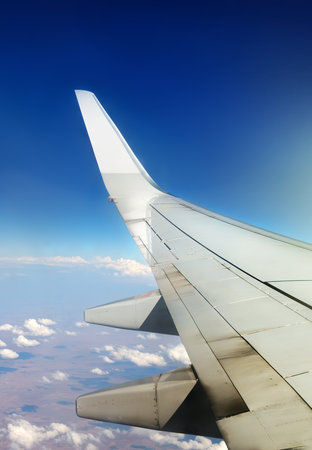 Wing of plane in sky and white cloudsの写真素材