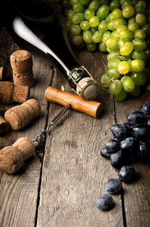 Wine with grape and corks on wooden tableの写真素材