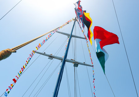 Flags of different countries on the mast of sailboat