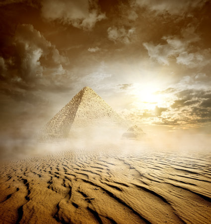 Storm clouds and pyramids in sand desertの写真素材