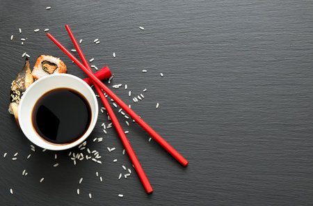 Soy sauce in bowl and sushi on slate tableの写真素材