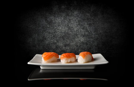 Three sushi on white plate and black backgroundの写真素材