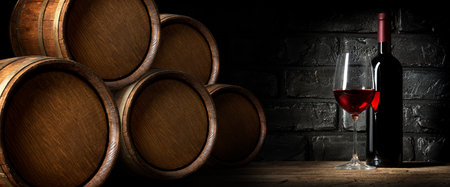 Red wine near barrels in cellar of wineryの写真素材