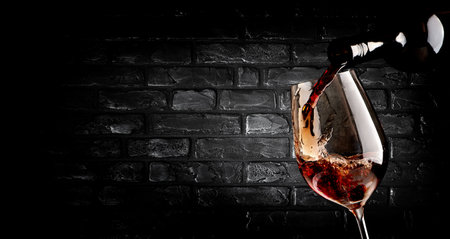 Wine pouring in wineglass near brick wallの写真素材